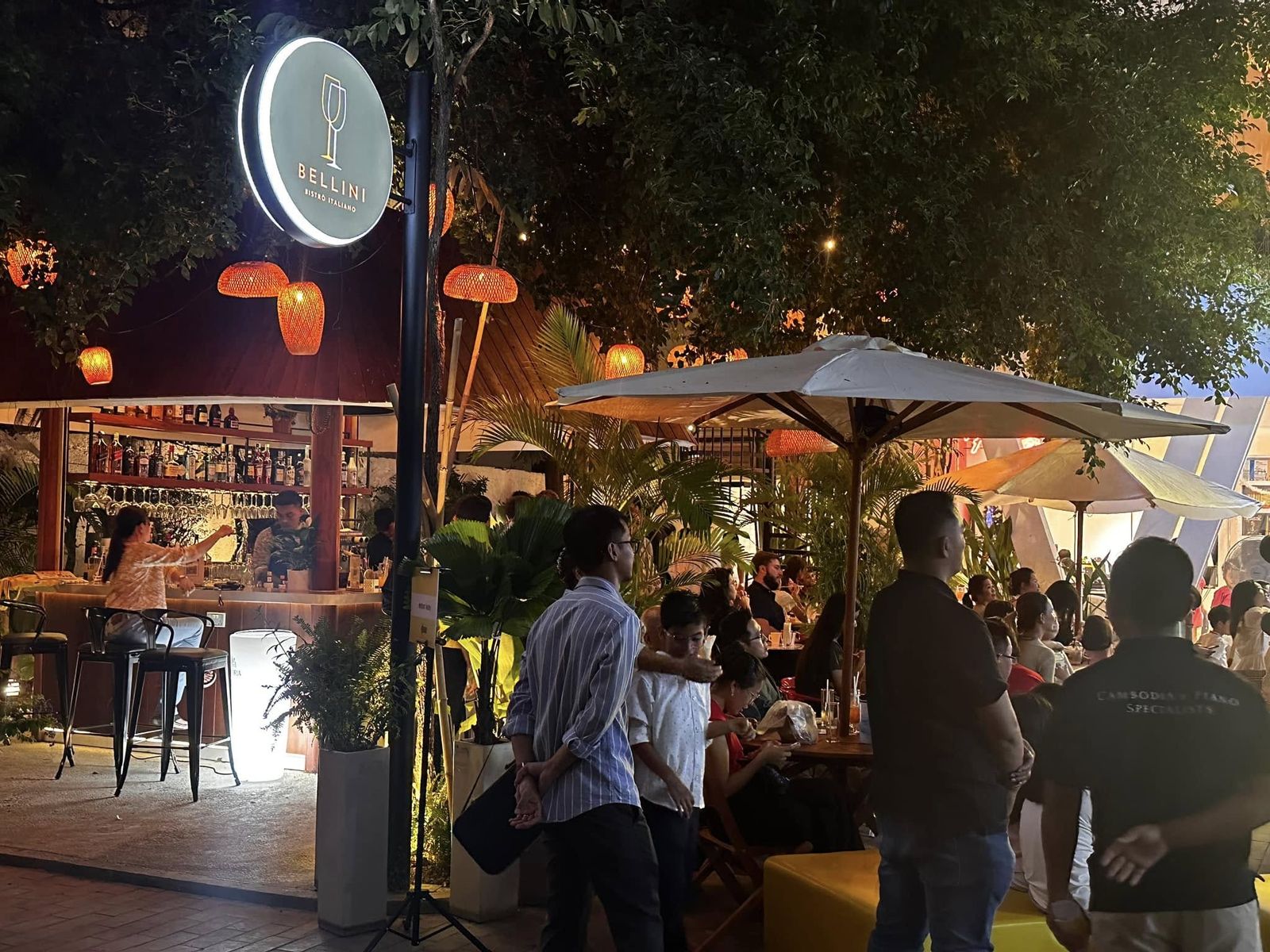 Illuminated Bellini Bistro Italiano sign at the entrance, garden and bar at night