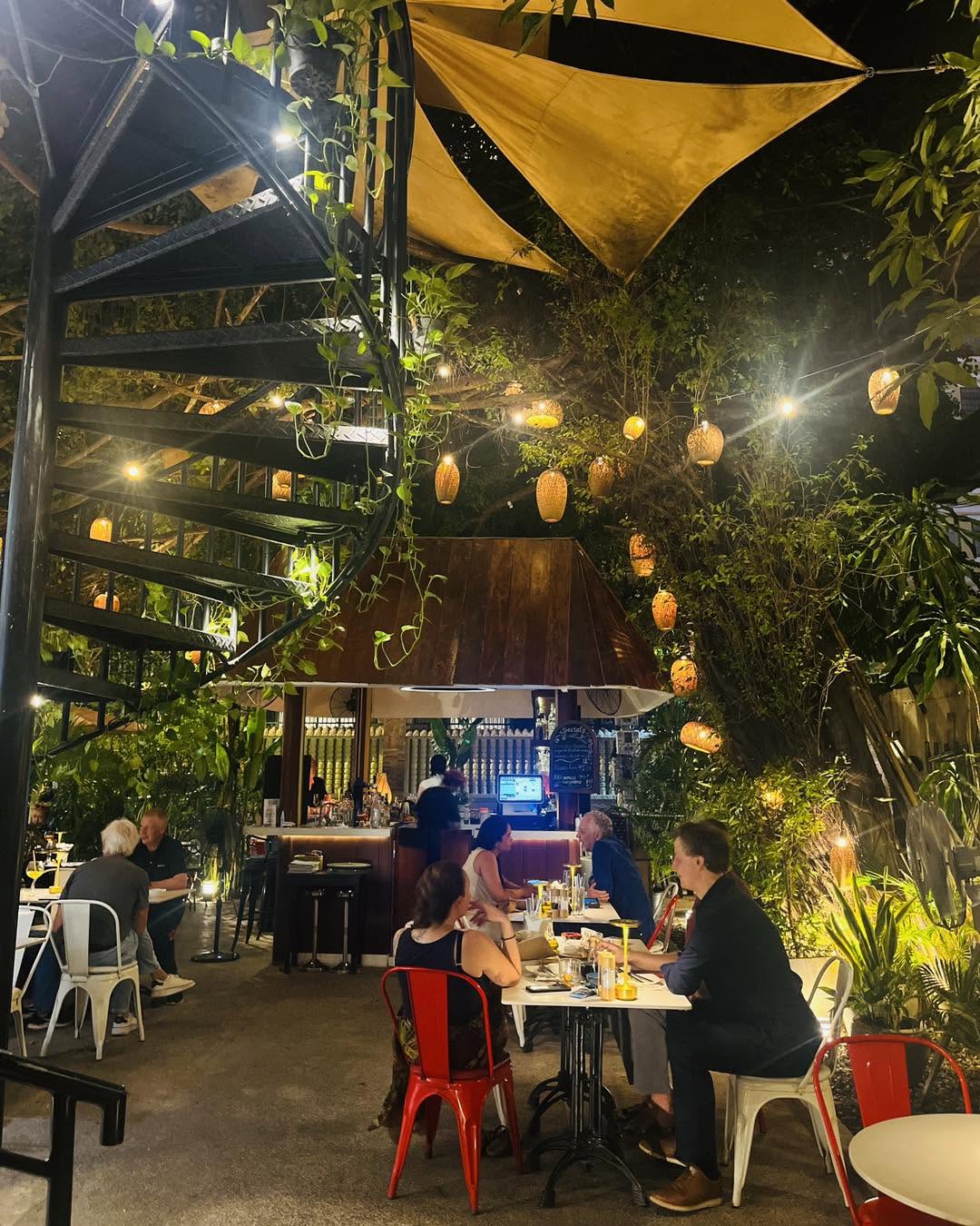 Bellini bar and spiral staircase at night, guests dining under string lights